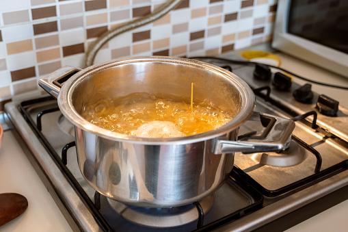 Cooking spaghetti in the boiling water contained in a saucepan