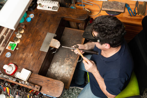 istock a goldsmith holds a silver ring and shapes it with a mold and a hammer. 1308076344