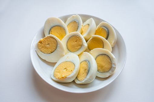 Small quail eggs in a shopping cart on a yellow background, healthy food