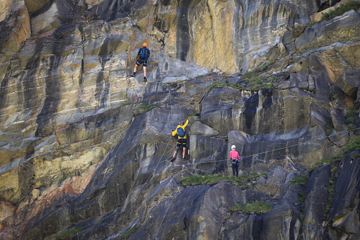 6.07.2020 - Austria Three ferrata climbers try to climb a rock along Stausee Mooserboden dam in Austrian resort of Kaprun in Zell am see District. Dangerous sport involving special climbing equipment.