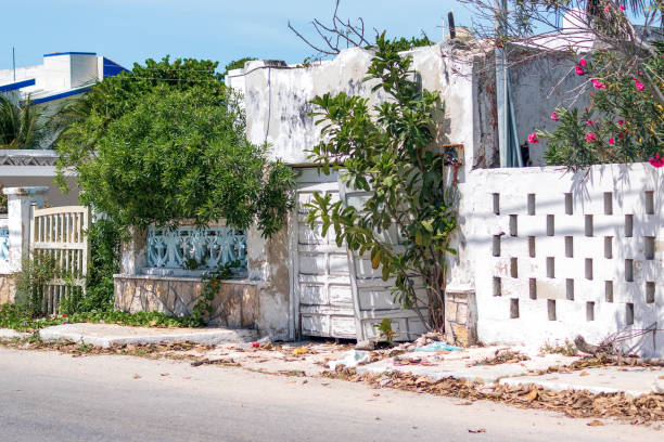 A view from the street of a humble town, with gates hanging askew having seen better days