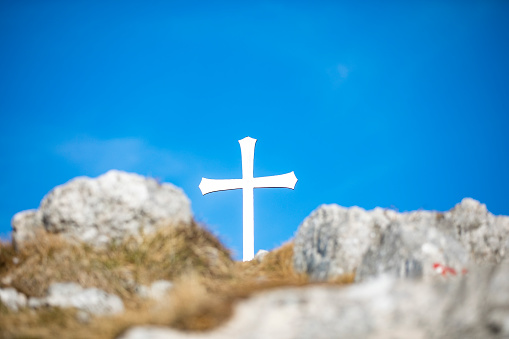 Metal Christian Cross on Top of a Hill Against Clear Blue Sky.