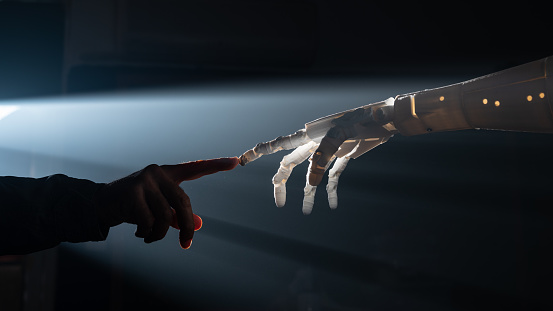 Human finger and robot's finger meet for collaboration between artificial intelligence and human intelligence concept. Back lit is used alongside foggy atmosphere for futuristic feel. Shot with a full frame mirrorless camera.