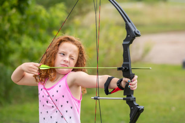 istock Girl Aiming Arrow As She Practices Archery Outdoors 1308083347