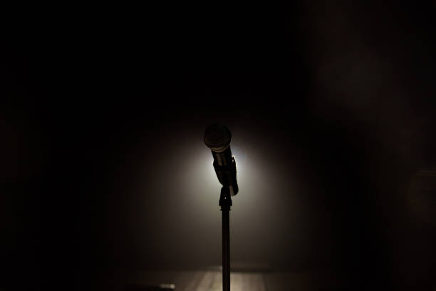 istock Close up of microphone on stage in black background 1308086802