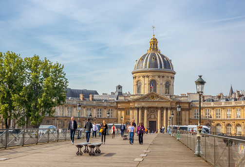 France, Paris - May 22, 2019: Summer day. People on the Footbridge of the Arts and Mazarine Library in the background