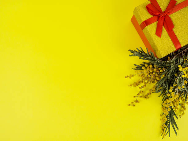 istock Mimosa and gift wrap on a yellow background. Festive postcard. Place for your text. 1308089228