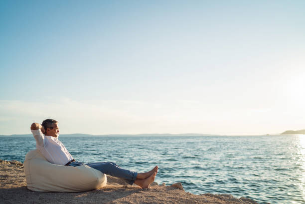 istock Senior man lying on deck chair on the beach 1308090698
