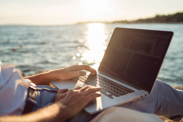 istock Senior man working on his laptop lying on deck chair on the beach 1308090706