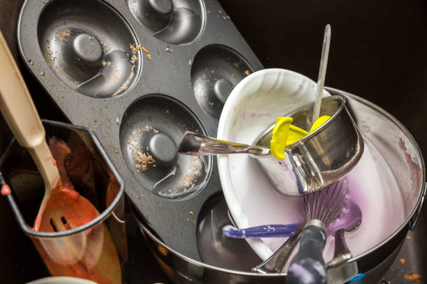 Dirty baking dishes in sink with donut pan and measuring cup