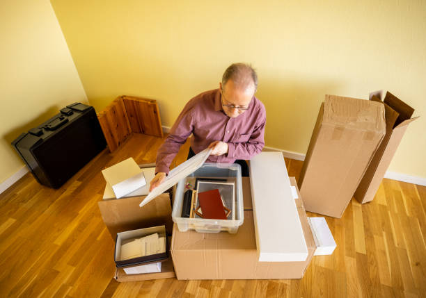 istock Middle aged caucasian man in empty apartment room, unpacking from cardbox boxes for moving house 1308094154