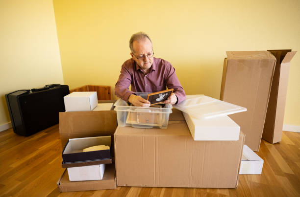 istock Middle aged caucasian man in empty apartment room, unpacking from cardbox boxes looking at picture frame 1308094158