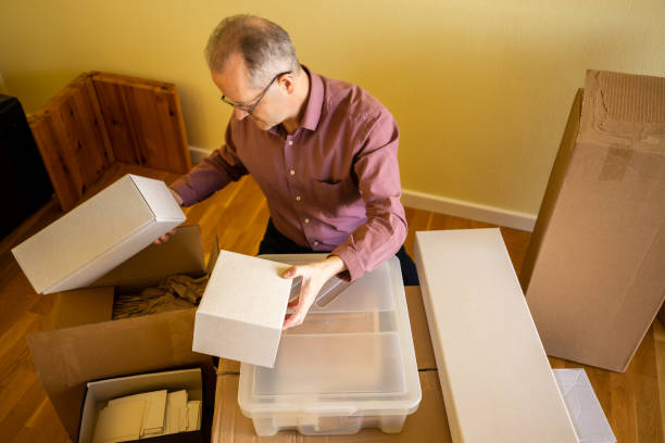 istock Middle aged caucasian man in empty apartment room, unpacking from cardbox boxes for moving house 1308094337