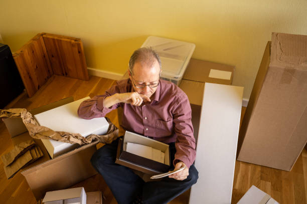 istock Middle aged caucasian man in empty apartment room, unpacking from cardbox boxes for moving house 1308094358