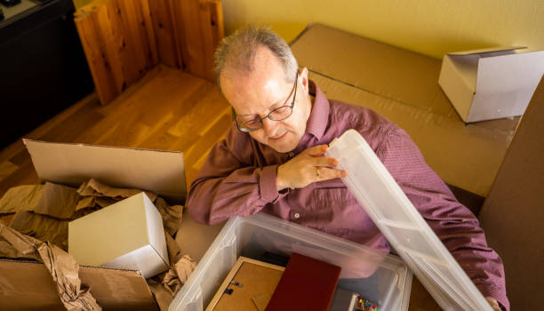 istock Middle aged caucasian man in empty apartment room, unpacking from cardbox boxes for moving house 1308095112