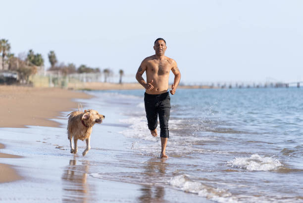 istock Man running on the beach with his dog. 1308095430