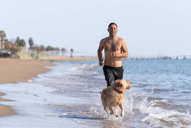 istock Man running on the beach with his dog. 1308095452