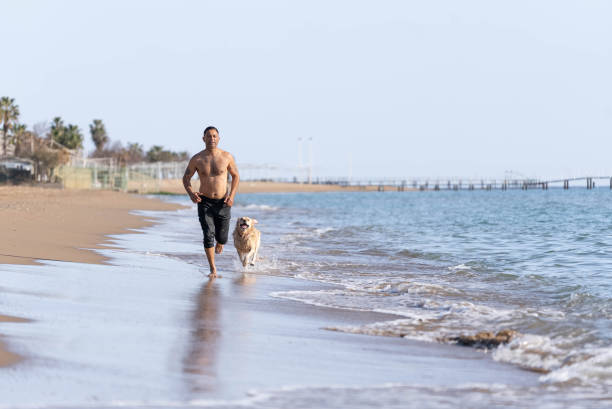istock Man running on the beach with his dog. 1308095480