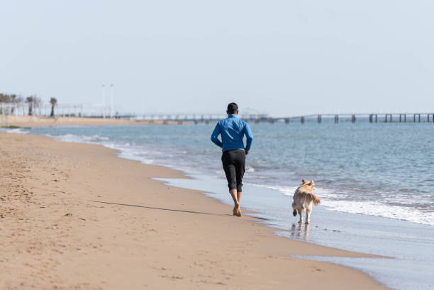 istock Man jogging on the beach with his dog. 1308095521