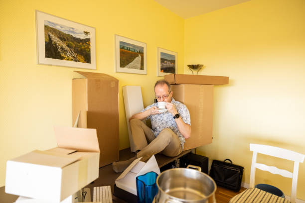 istock Senior single man in empty office apartment room, resting and taking a break from moving in or moving out, surrounded by cardboard boxes 1308095908