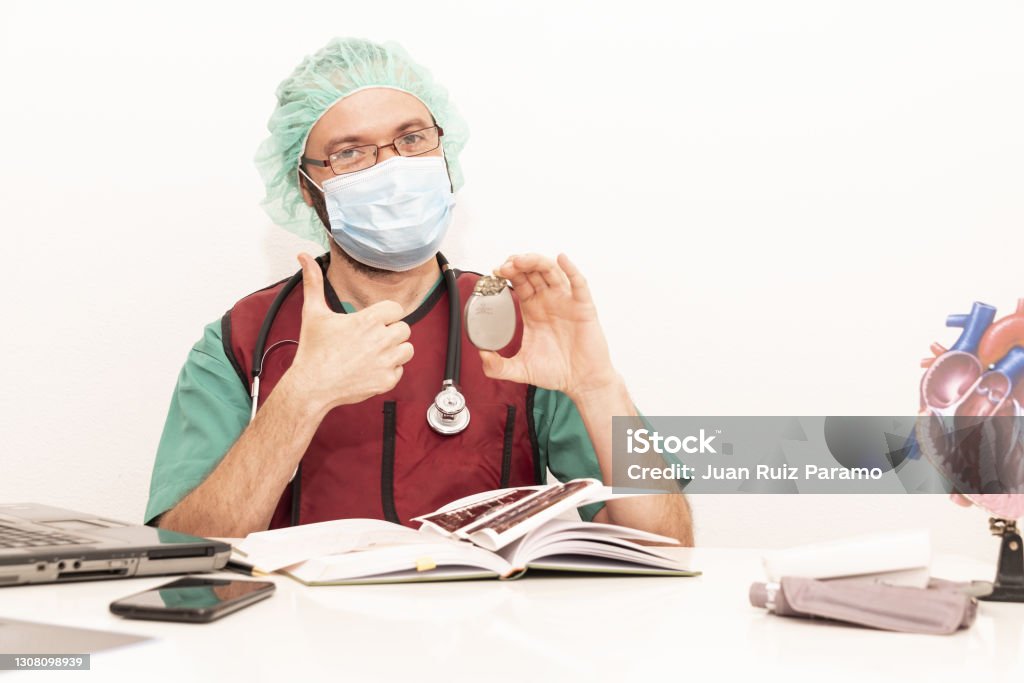 Cardiologist doctor working in his office wearing an operating theatre suit and lead x-ray protective equipment, white background. 40-44 Years Stock Photo