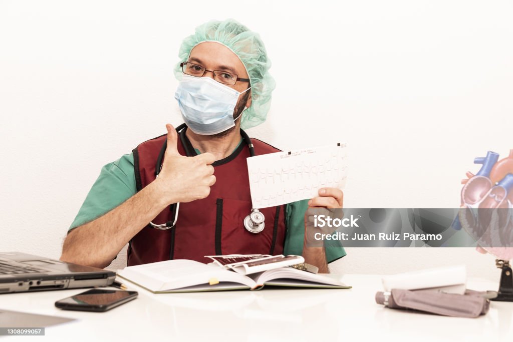 Cardiologist doctor working in his office wearing an operating theatre suit and lead x-ray protective equipment, white background. 40-44 Years Stock Photo