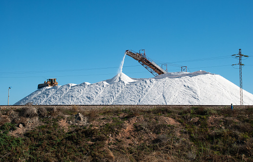 Extraction of salt and pouring it into one big heap with the help of equipment at Tunisia.