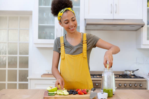 istock Mixed race woman making a healthy drink and smiling in a kitchen 1308101257