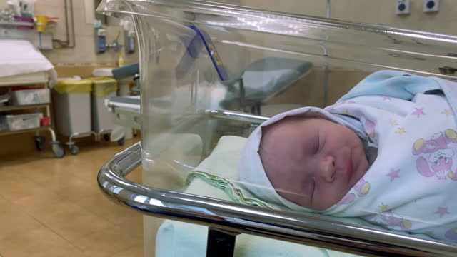 Newborn baby boy inside crib in maternity hospital delivery room