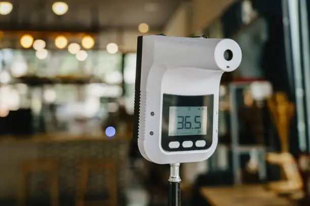Photo of Infrared Thermometer or Handheld Digital Thermometer stand in front of coffee shop