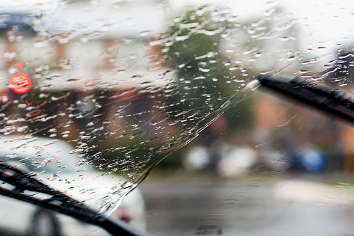 Blurred image of heavy torrential rain through the windscreen. Cars with headlights are barely seen on the road. Sydney flash flooding warning.