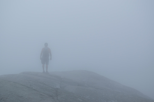 Man in the fog on top of a mountain