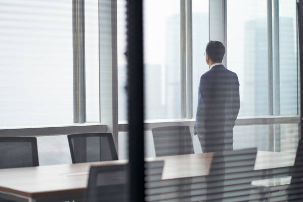istock asian business man standing in front of window thinking 1308110451