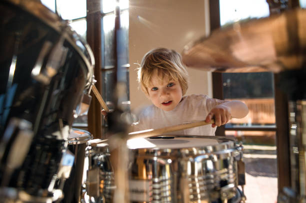 istock Front view of small boy indoors at home, playing drums. 1308114451