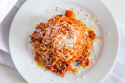 Top view of Plate of spaghetti with tomato and bacon and pecorino cheese