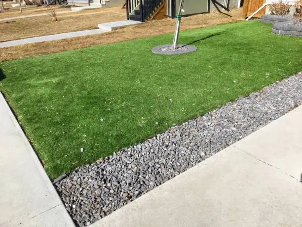 Photo of A beautiful artificial lawn in the front yard shining a healthy green in winter while other lawns are yellow and brown