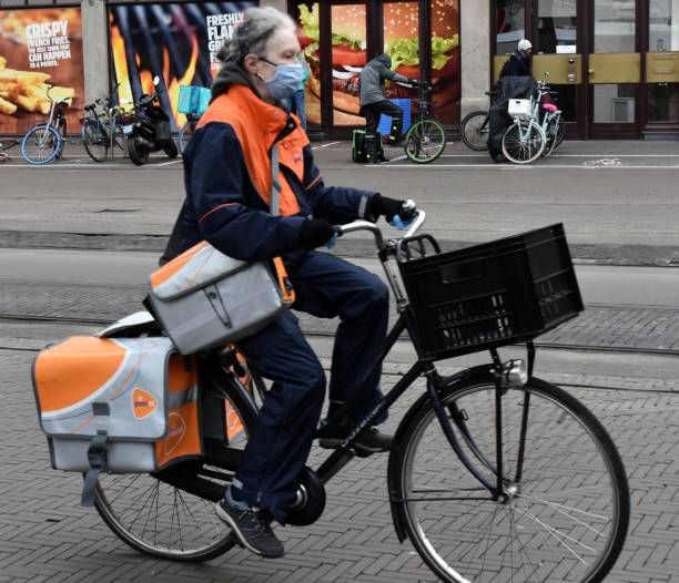 PostNL Delivery Worker Carrying Package To Clients With Bicycle During Winter Season In The Hague South Holland The Netherlands Europe