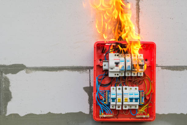 burning switchboard from overload or short circuit on wall closeup - electricity fire circuit board short imagens e fotografias de stock