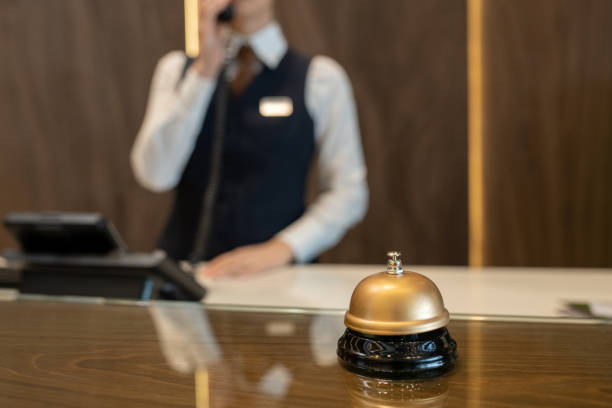 電話で女性受付コンサルティングクライアントに対する木製のレセプションカウンターのベル - hotel hotel reception bellhop concierge ストックフォトと画像