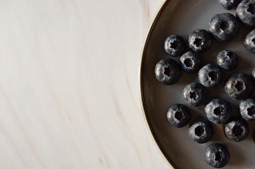 Istanbul, Turkey-March 14, 2021: A Section of Blueberries on a tumbled gray plate on a white-gray marble background, Full Frame, Still life, Studio shot, Flat lay. Shot with Canon EOS R5.