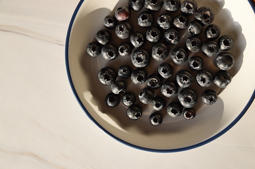 Istanbul, Turkey-March 14, 2021: Blueberries on a tumbled gray plate on a white-gray marble background, Full Frame, Still life, Studio shot, Flat lay. Shot with Canon EOS R5.