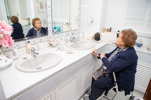 Older woman in her bathroom, to get pretty. Senior woman in the bathroom