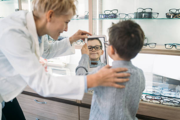 istock Smiling boy, looking at himself in a mirror showing his new glasses 1308139032