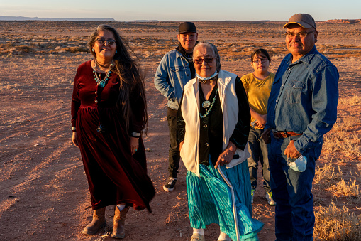 A Happy Smiling Native American, Navajo Family Gather Outside Their Home In Monument Valley Tribal Park, Utah Near Sunset