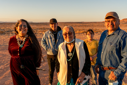 Feliz nativo americano sonriente, familia Navajo se reúnen fuera de su casa en Monument Valley Tribal Park, Utah cerca de sunset photo