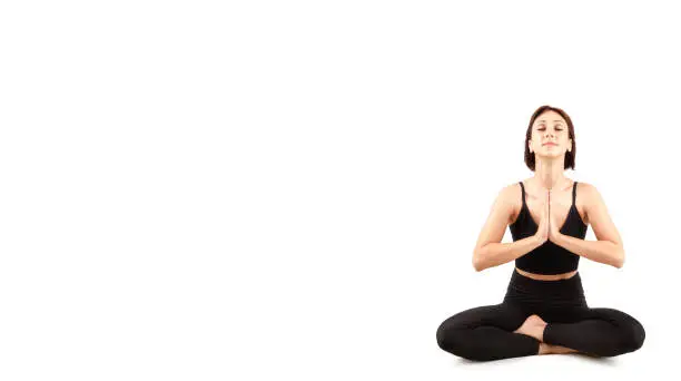 Photo of a female athlete in a black tight-fitting suit, doing gymnastics and yoga, isolated on a white background