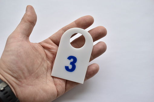 Clothing tag with number three in hand