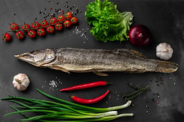 dried pike fish with vegetables on a black background top view, concept of farmers market