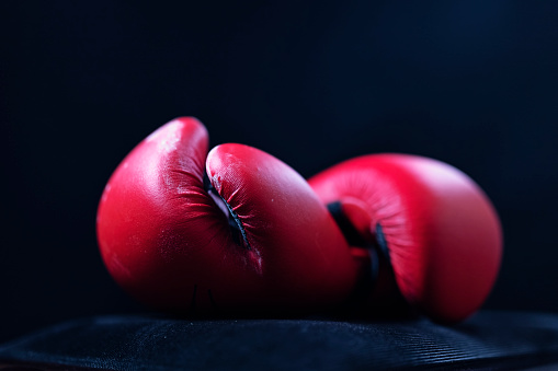 Shallow depth of field, red boxing gloves on black background.