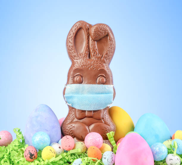 istock Chocolate Easter bunny, surrounded by Easter eggs, wearing a medical face mask for protection to the coronavirus 1308157471